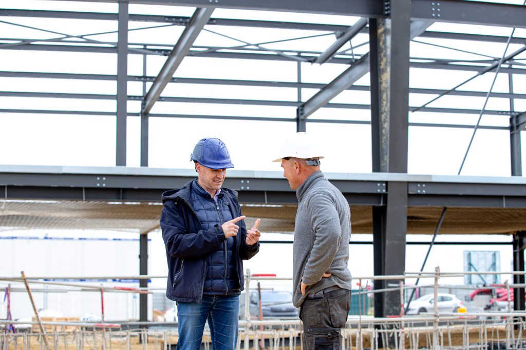 Le contractant général d’Aedifici'hom, Nicolas DORGLER, échange avec un artisan sur un chantier de construction en Île-de-France.
