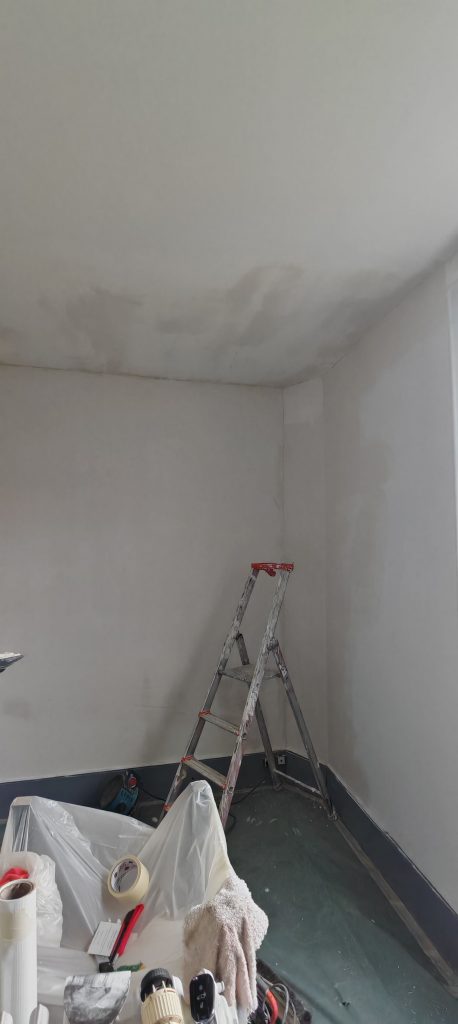 Travaux de rénovation sur un mur après dégât des eaux, avec enduit appliqué en attente de peinture. Géré par l'entreprise Aedifici'hom et son dirigeant Nicolas DORLGER, contractant général du bâtiment.