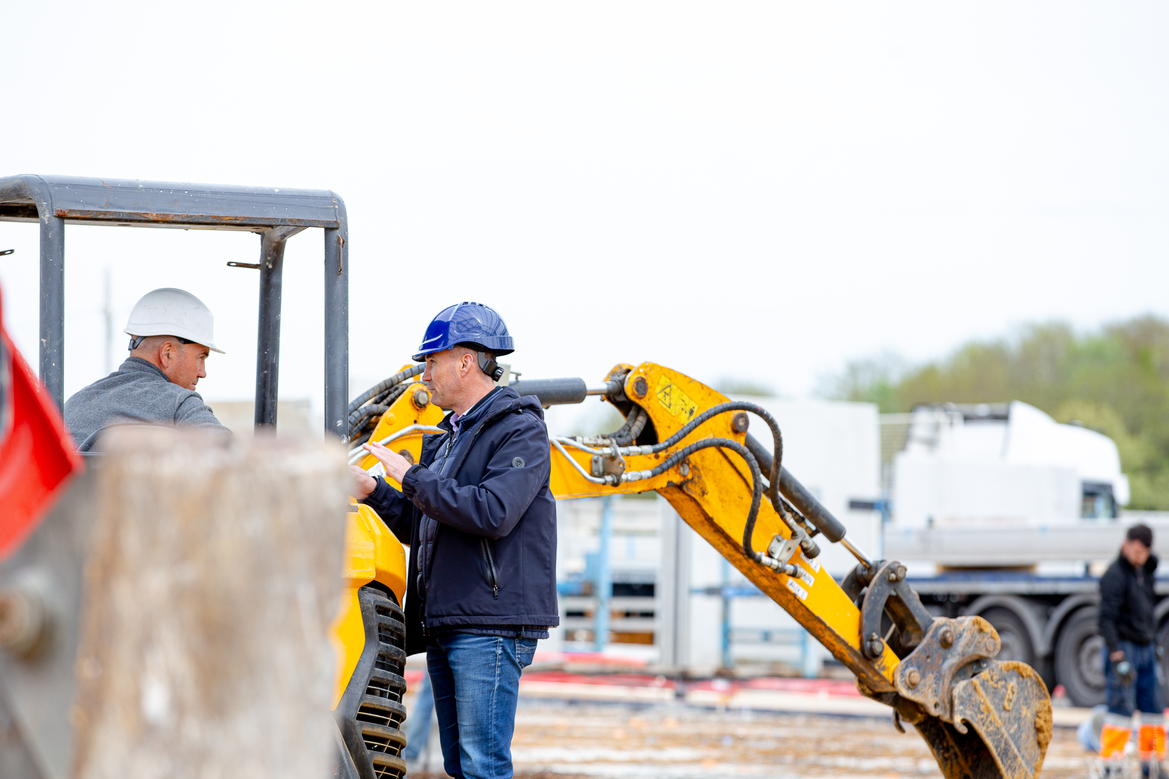 Le dirigeant d’Aedifici'hom, Nicolas DORGLER, échange avec un ouvrier sur son engin de chantier, en pleine discussion sur site.