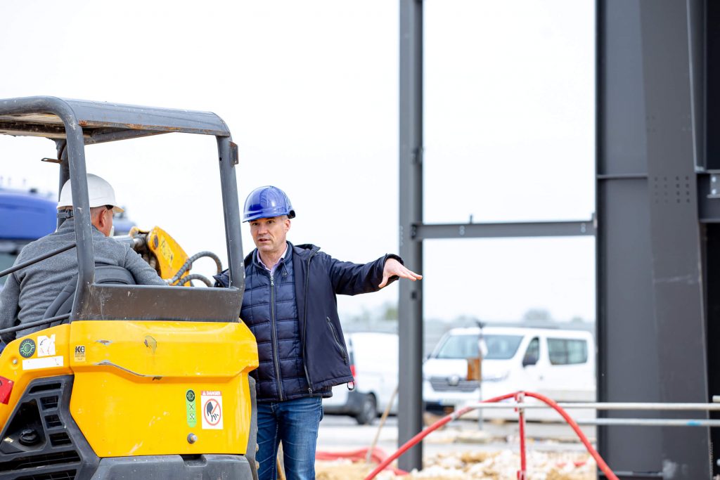 Contractant général en Seine-et-Marne (77), le dirigeant d’Aedifici'hom, Nicolas DORGLER, donne ses instructions à un ouvrier sur chantier, casque sur la tête.