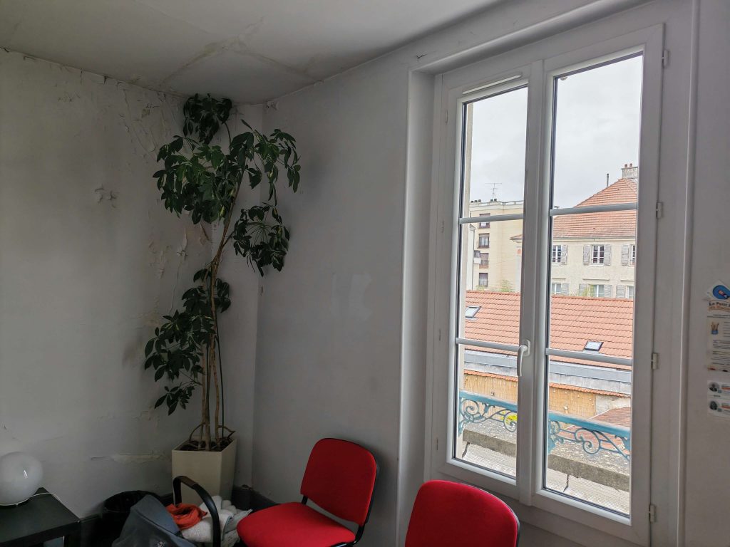 Pièce touchée par un dégât des eaux, avec mur fissuré et mobilier de type salle d’attente.