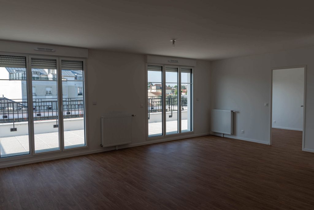 Grande pièce principale lumineuse dans un appartement neuf, avec deux fenêtres donnant sur l’extérieur, livré sous la responsabilité de Nicolas DORGLER alors conducteur de travaux.