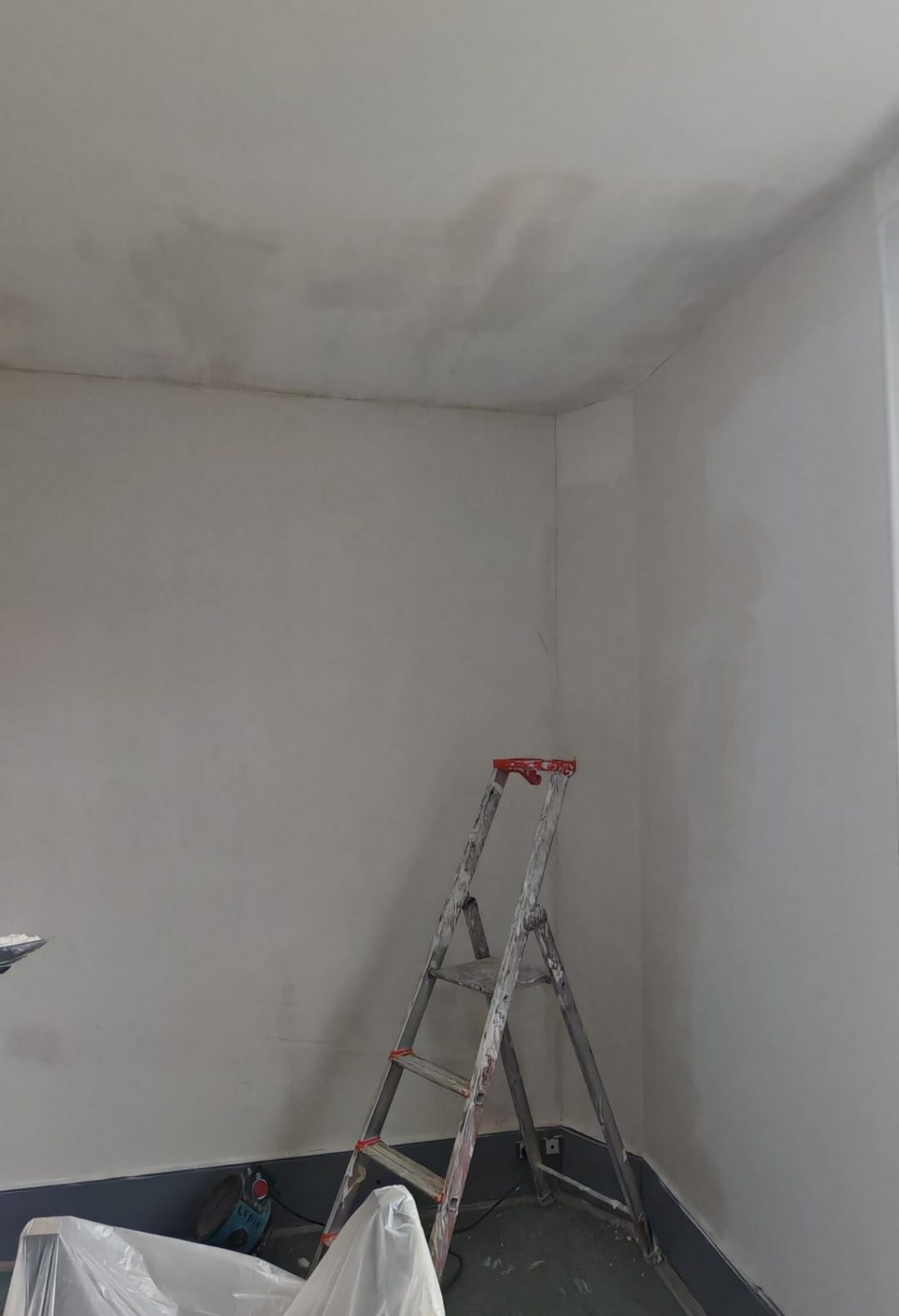 Travaux de rénovation sur un mur après dégât des eaux, avec enduit appliqué en attente de peinture. Géré par l'entreprise Aedifici'hom et son dirigeant Nicolas DORLGER, contractant général du bâtiment.