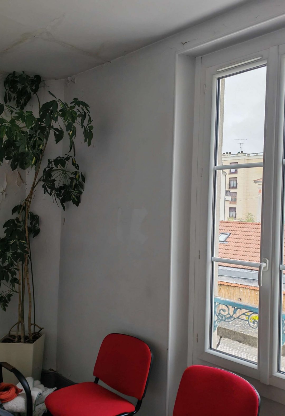 Pièce touchée par un dégât des eaux, avec mur fissuré et mobilier de type salle d’attente.